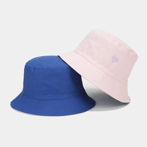 Détail de bobs en coton bleu et rose avec petite broderie de cœur violet