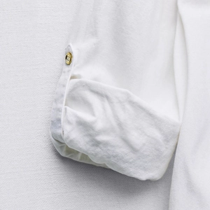 White linen blend shirt featuring rolled sleeves with adjustable golden buttons detail