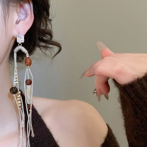 Macro shot of Bohemian tassel earrings featuring amber beads and silver needle studs