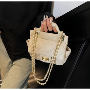 Close-up of beige quilted crossbody bag with gold twist lock and metal chain strap