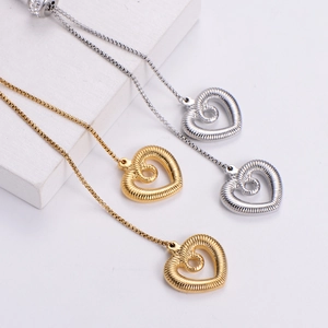 Minimalist gold and silver heart pendant necklaces with spiral texture on white display