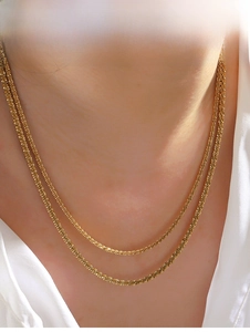 Detailed view of gold double-layered woven sparkling choker chains on a model neck