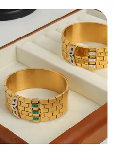 Detailed macro of 18K gold plated brick-pattern bangles with green gems and diamonds