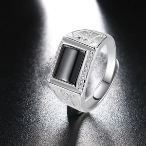Detailed macro shot of a men's silver ring featuring a black stone and side crystal accents
