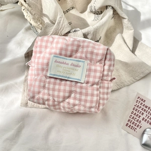 Dettaglio macro della borsa per cosmetici trapuntata a quadretti rosa con cuciture a cuore