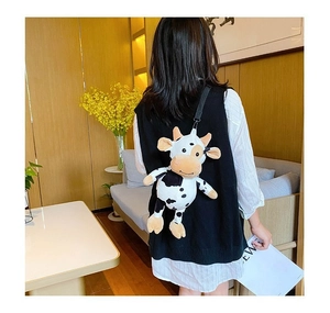 Rear view of a girl wearing a cute white and black plush cow shaped backpack with straps