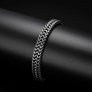 Gros plan détaillé d'un bracelet gourmette en acier inoxydable gris foncé à maille en V