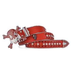 Macro detail of red crocodile leather belt with skull buckle and rhinestone studs