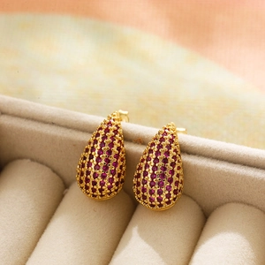Macro shot of luxury gold-plated drop earrings with micro-pave purple zircon stones
