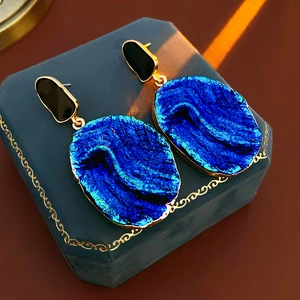 Detail von Vintage-Ohrringen mit blauer Steinstruktur und goldenen Metallkanten