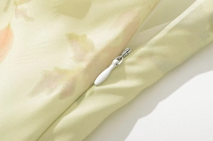 Détail d'une fermeture éclair blanche invisible sur le tissu d'une robe à fleurs