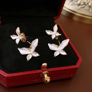 Boucles d'oreilles papillon dorées en émail blanc sur écrin à bijoux rouge