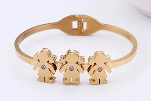 Detailed macro of gold open bangle with three little girl charms and tiny zircon stones