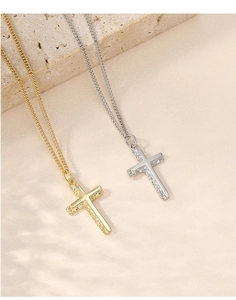 Detail view of gold and silver S925 cross necklaces resting on a beige stone base