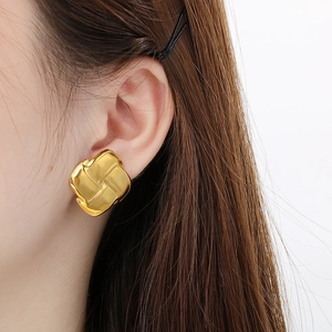 Square gold stainless steel stud earrings with woven texture worn by a model