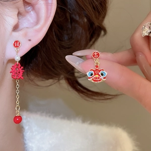 Détail de boucles d'oreilles lion de danse rouge et or avec caractères chinois et perles