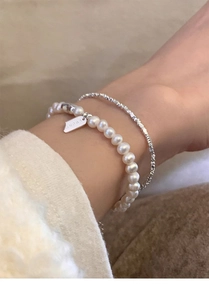 Detail of s925 silver bracelet with freshwater pearls and a Lucky engraved square charm