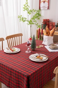 Close-up of red and black festive plaid tablecloth with gold thread and tassel detail