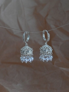 Detailed macro of silver Jhumka bell earrings with sparkling zircon and pearl tassels
