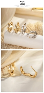 Close-up of gold cross hoop earrings with inlaid zircons on a vintage silk background