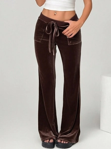 Detail of dark brown velvet flared trousers with drawstring waist on female model
