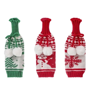 Three knitted Christmas wine bottle covers with snowman and tree patterns on white background