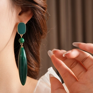 Detail of a vintage-style earring with green malachite stone drop pendant on a model