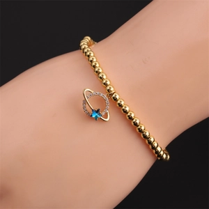 Minimalist gold beaded bracelet featuring a Saturn pendant with a blue star and zircon