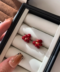 Detailed macro view of red berry stud earrings with center zircon and gold base