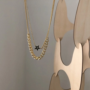 Double layered gold necklace featuring a thin bead chain with black star and a thick Cuban link