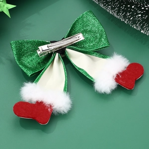 Close-up of sparkling green sequin bow hair clip with plush red Christmas boot charms