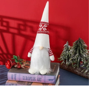 Detail of Christmas gnome with white snowflake hat standing on books by a red wall