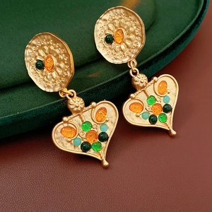 Macro view of vintage heart drop earrings with colorful gemstones on a velvet box