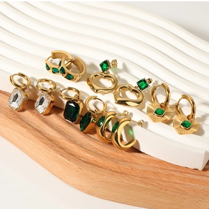 Macro view of vintage gold-plated heart earrings with emerald stones and zircon details