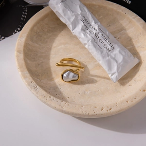 Detail of 18K gold stainless steel ring with baroque pearl on a stone tray