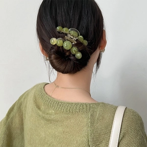 Close-up of a green translucent spherical claw clip styled on a woman's hair back view