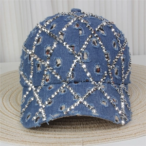 Detail of blue denim baseball cap with silver metal rivets and distressed torn fabric