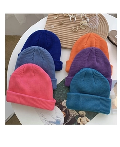 Flat lay of colorful thick knit beanies in various shades on a minimalist table