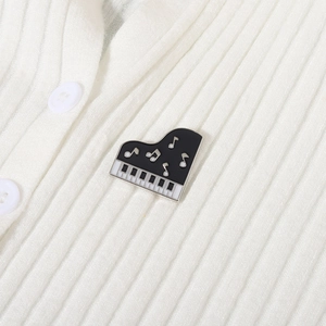 Elegant piano enamel brooch pin with musical note detail on white knit fabric background