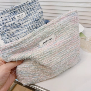 Detailed macro of woven tweed makeup bags featuring the simple wish brand label