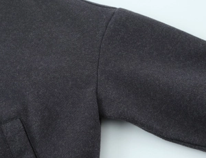 Close-up of high-quality wool fabric texture and stitching on dark grey bomber jacket