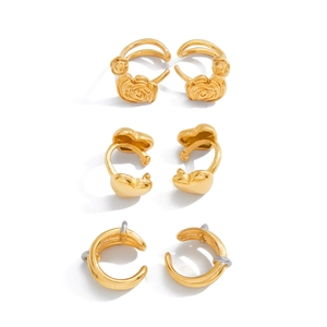 Drei Paar elegante goldene Herz-, Rosen- und C-förmige Ohrringe auf weißem Hintergrund