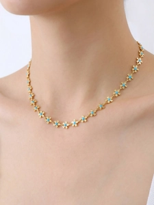 Détail du collier à fleurs en émail bleu en acier inoxydable doré sur le cou d'un modèle