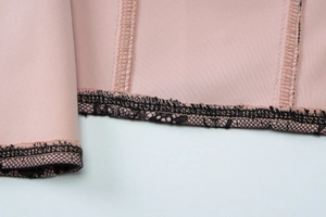 Détail du tissu extensible rose avec dentelle noire et coutures renforcées sur haut corset