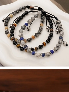Close-up of adjustable stone bead bracelets with tiger eye and lapis lazuli on ceramic tray