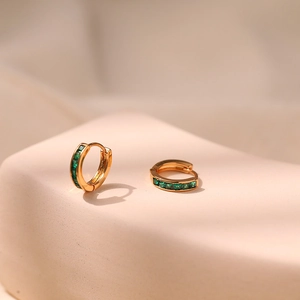 Close-up of small 18K gold earrings with emerald green square-cut zircon stones
