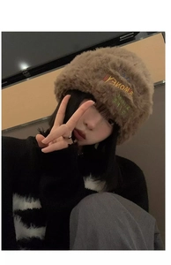 Detail of fluffy brown plush knit hat showing soft fuzzy texture and embroidered side patch
