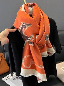 Orange thick scarf with horse pattern and fringe, draped over a black winter outfit
