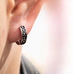 Detail view of vintage titanium steel hoop earring with embossed punk chain texture on the ear