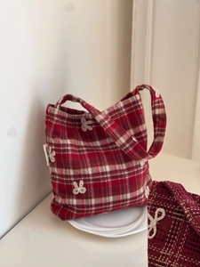 Detail of red plaid wool handbag with delicate lace bows and a minimalist design
